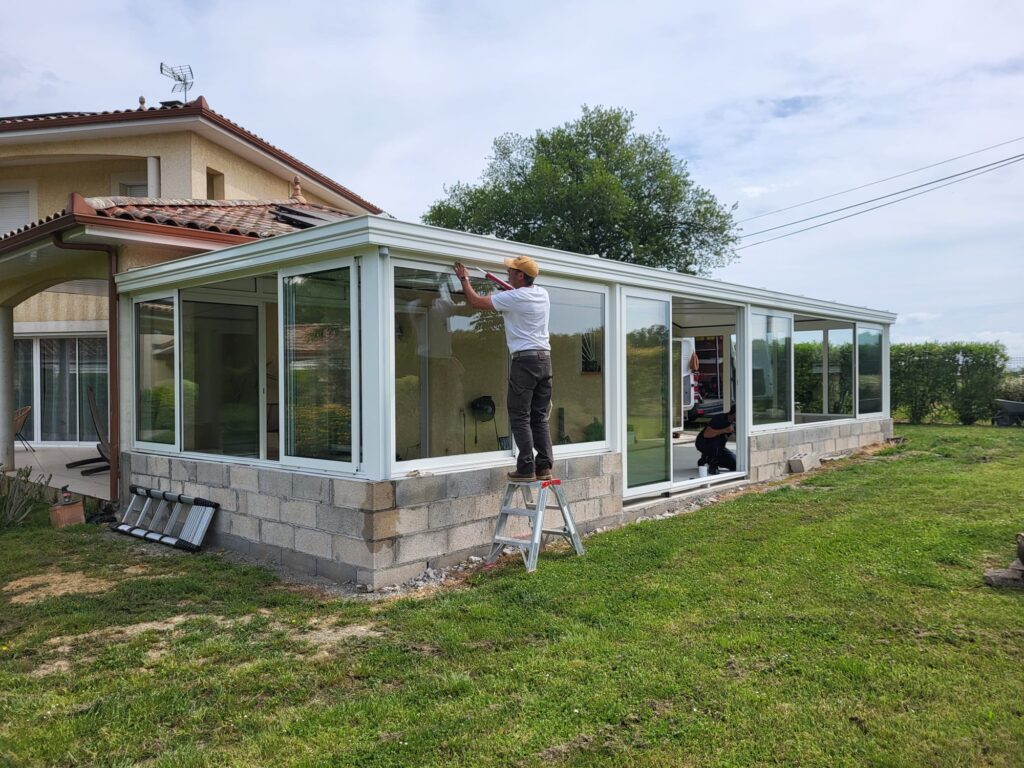 Véranda XXL blanche fabrication sur mesure et posée sur un muret existant pour les moments de réunions en famille - Gers et Toulouse