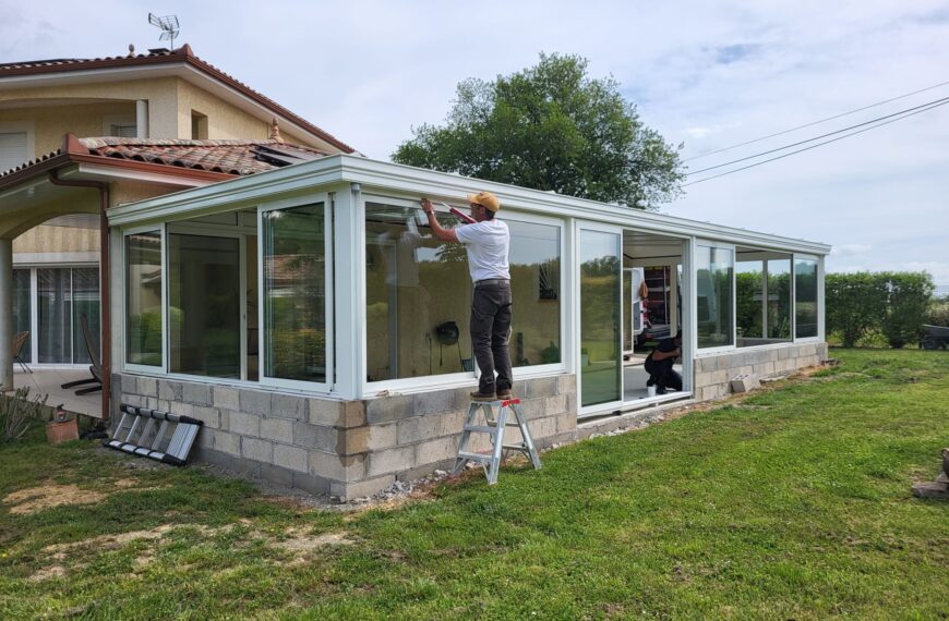 Véranda XXL blanche fabrication sur mesure et posée sur un muret existant pour les moments de réunions en famille – Gers et Toulouse